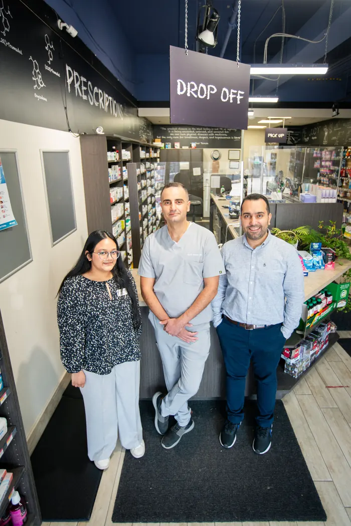 Pharmacy team standing beneath the prescription drop-off sign