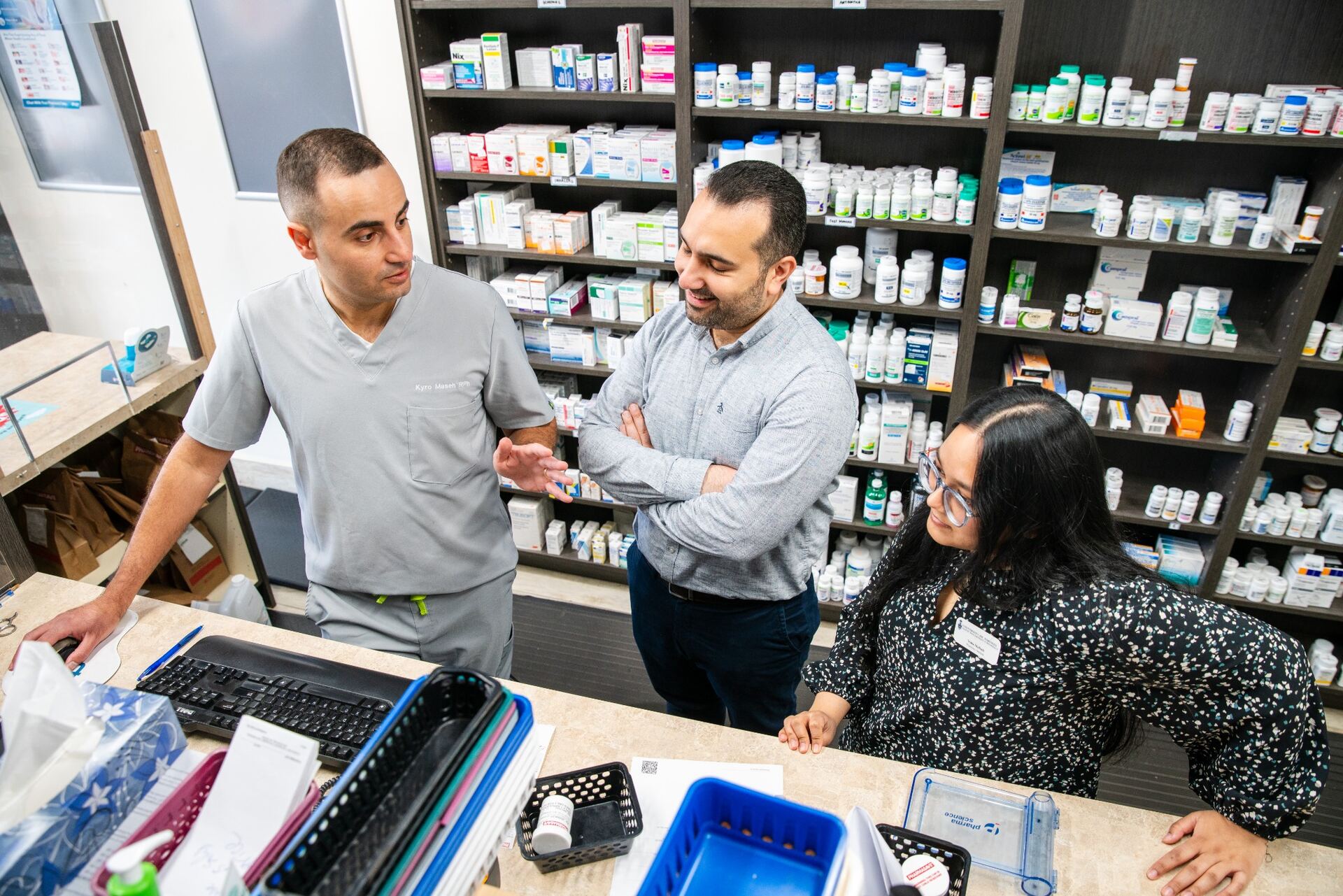 Kyro Maseh, pharmacist and founder, speaking with teammates at the pharmacy counter